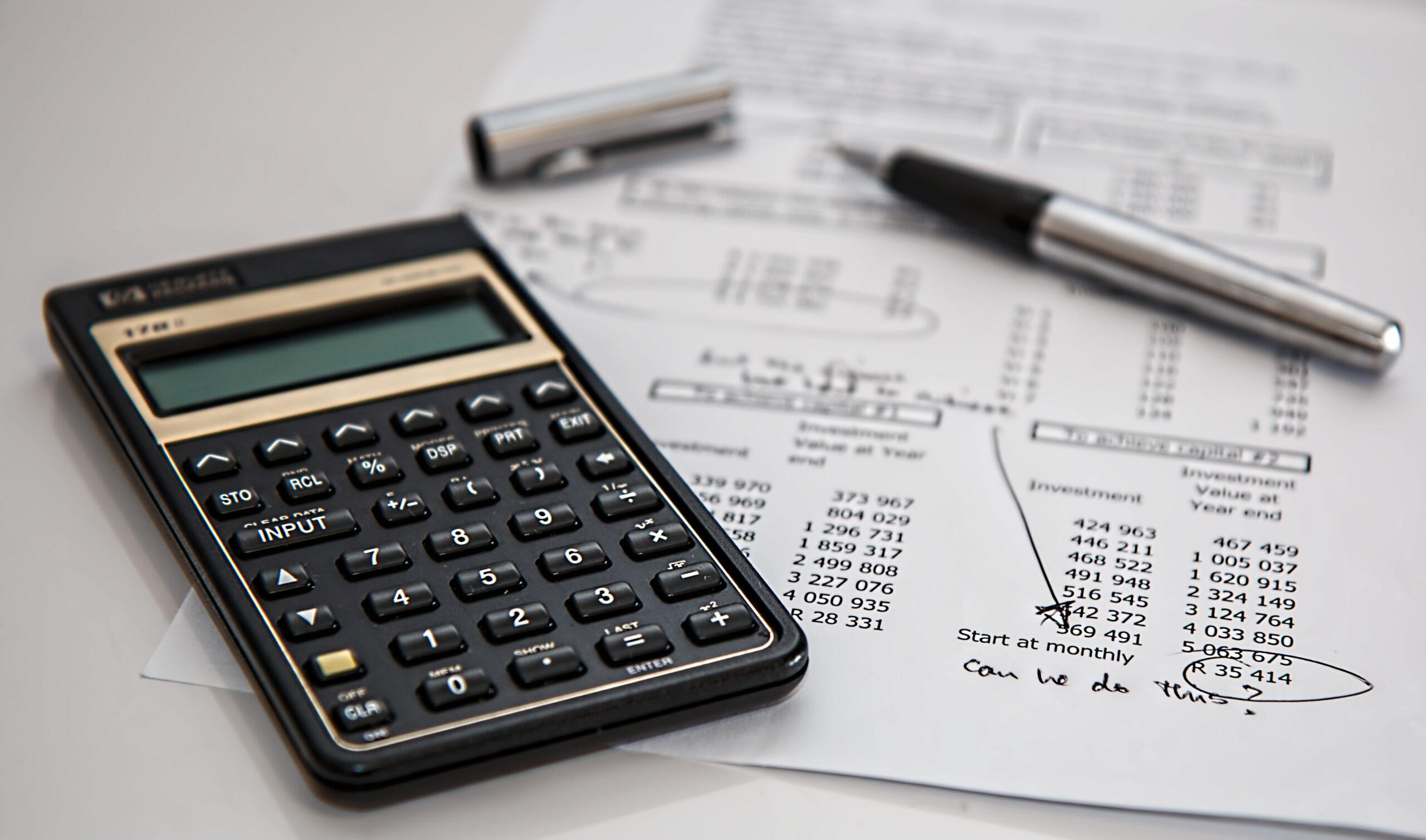 Kalkulator, długopis i dokument osoby planującej budżet firmy, leżące na stole